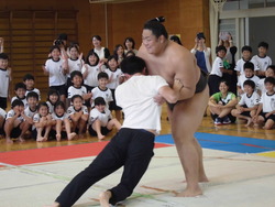 先生がお相撲さんを押している写真