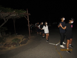 キャンプファイヤーでフォークダンスをしている写真