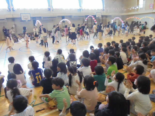 1年生が6年生と一緒に花輪をくぐっている写真