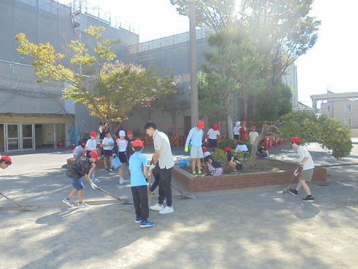 6年生が花壇の周りの草取りをしているところ